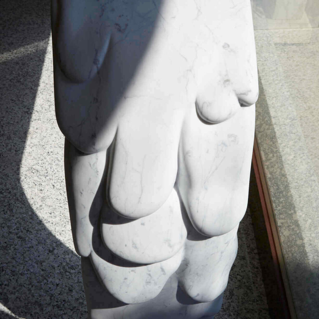 Close-up of the elegant curves on the white Carrara marble console, highlighting its sinuous design inspired by nature.